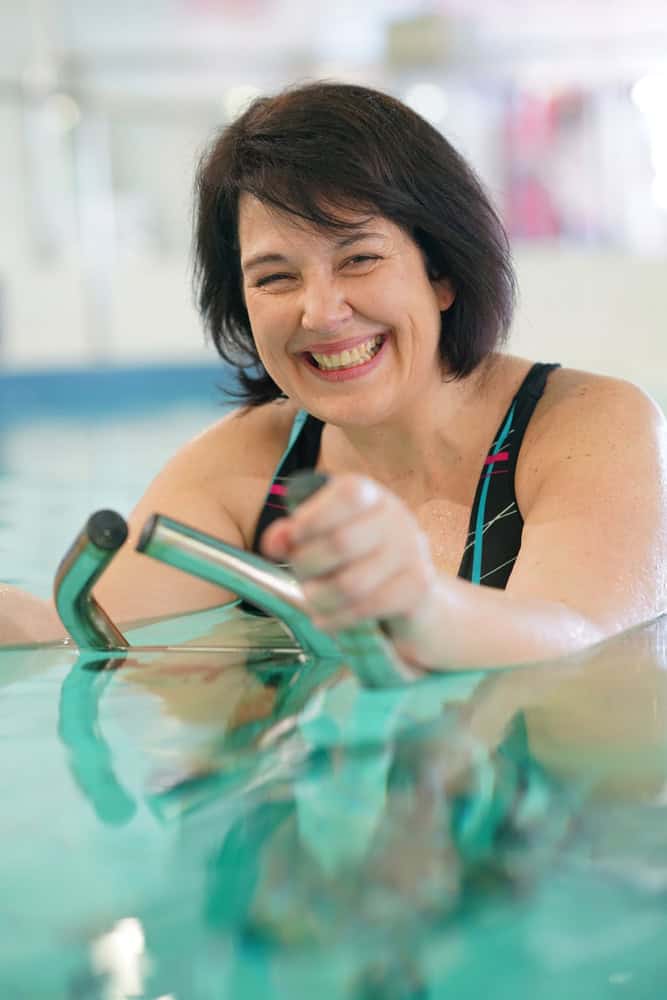 Femme dans le centre de spa faire des exercices aquabike